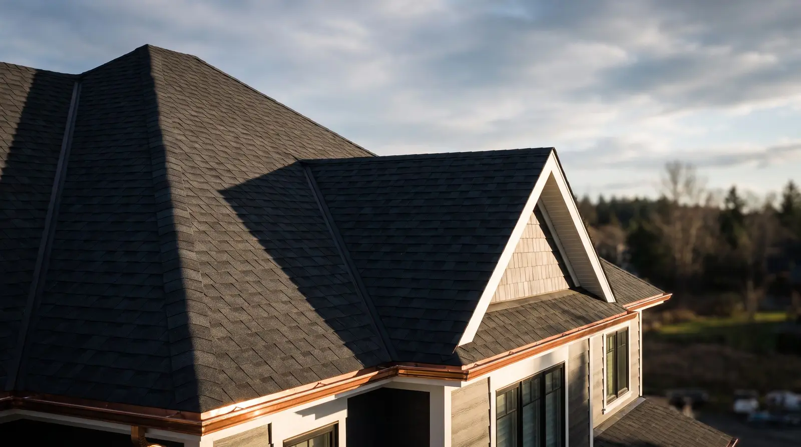 Roofing website design by The Quiet Protocol: a new dark shingle roof with copper flashing against an evening sky