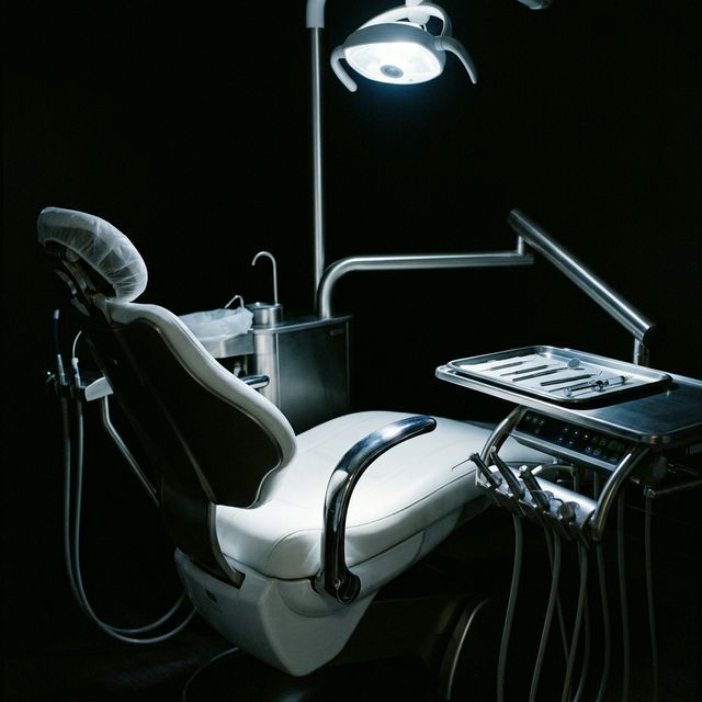 A dental treatment chair under clinical lighting in a dark room , the context of a dental practice installation.