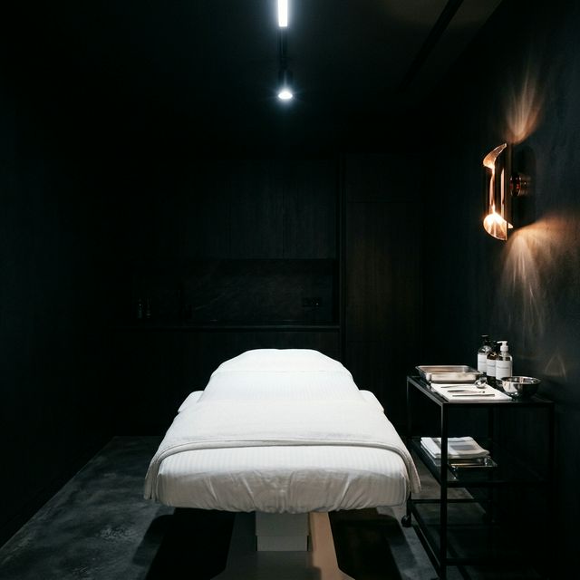 A medical spa treatment room with a white bed under cool LED light and a rose-gold sconce , the context of a med spa installation.