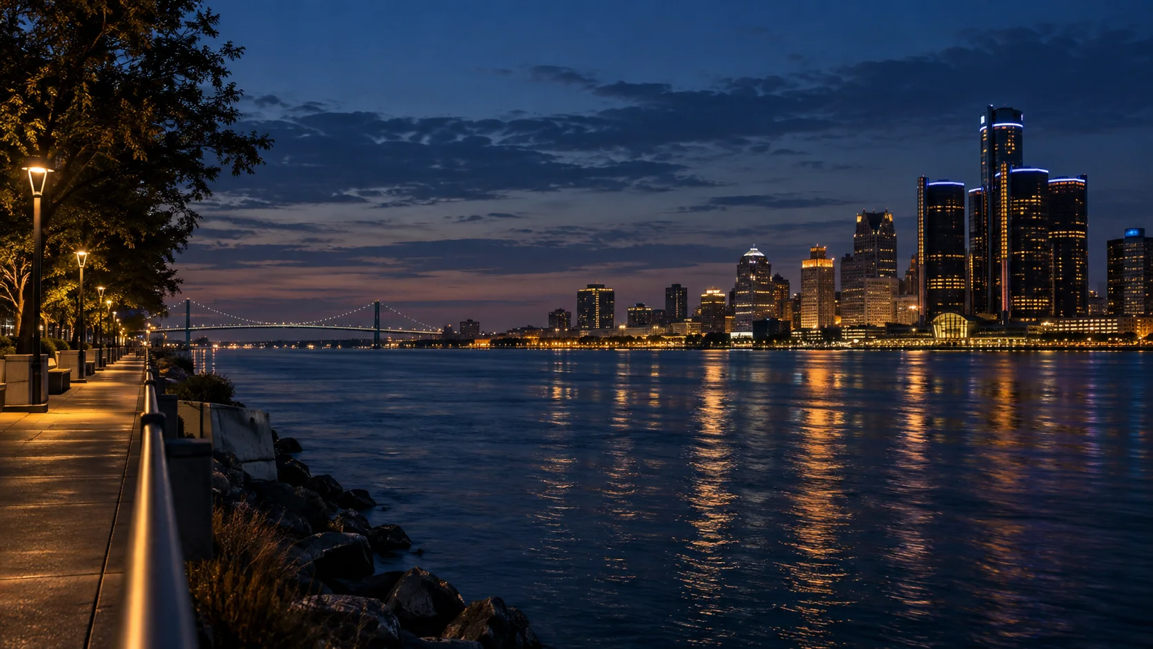 Windsor riverwalk at blue hour across the Detroit River from the Detroit skyline and distant bridge